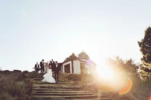 Wedding party on the stone steps below the Netherwood chapel at sunset