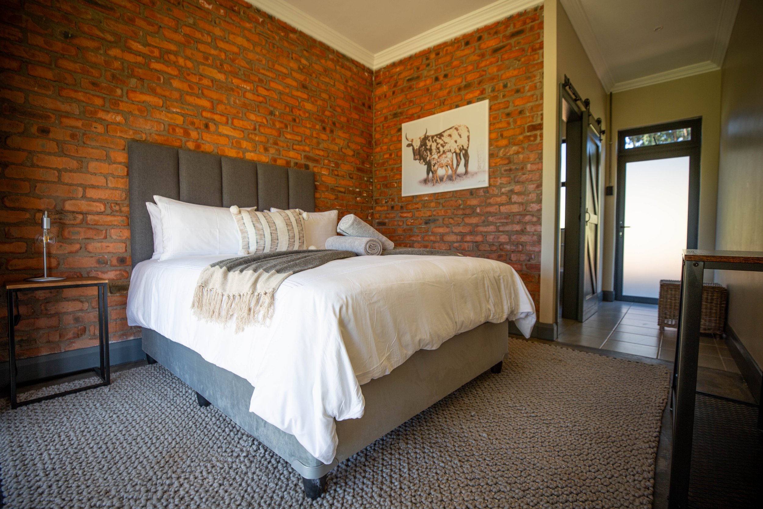 Queen bed against an exposed brick wall in Annex Room 1