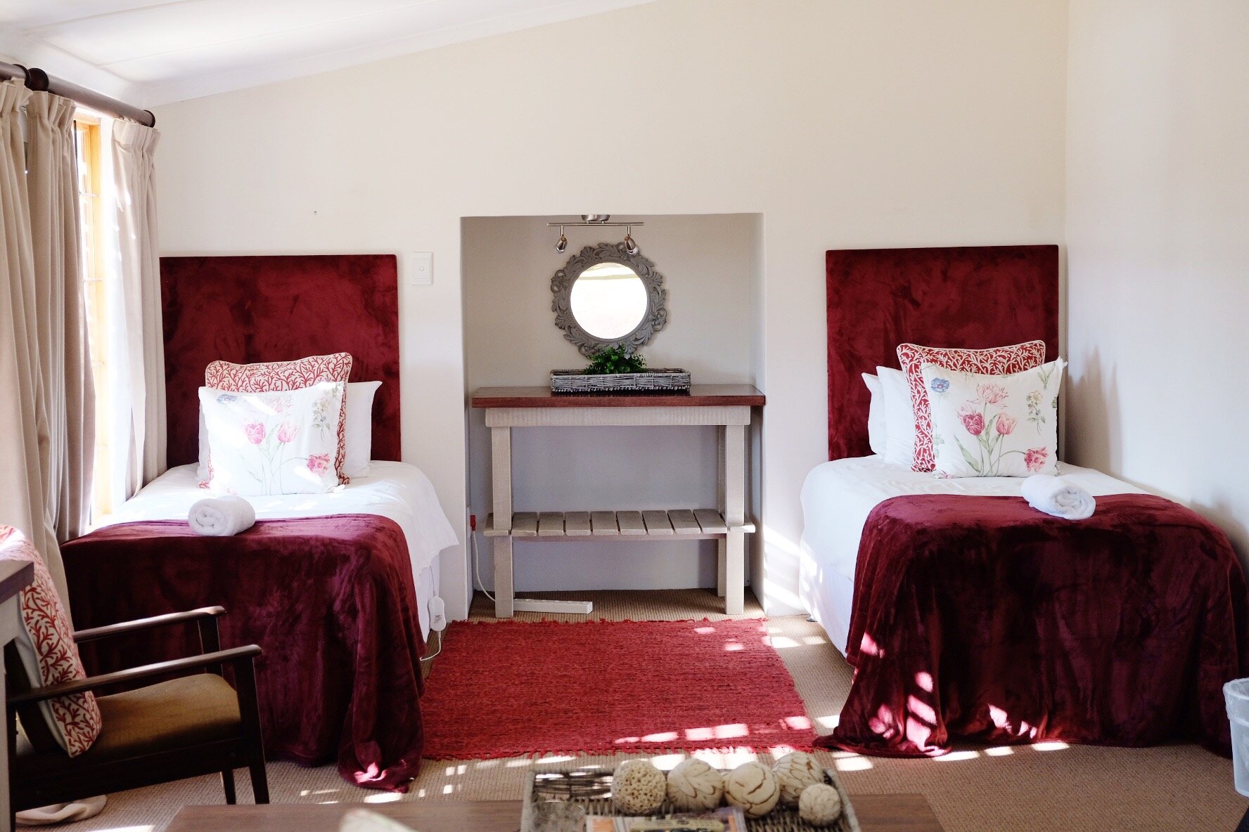 Twin beds with red velvet headboards in Ibis Cottage