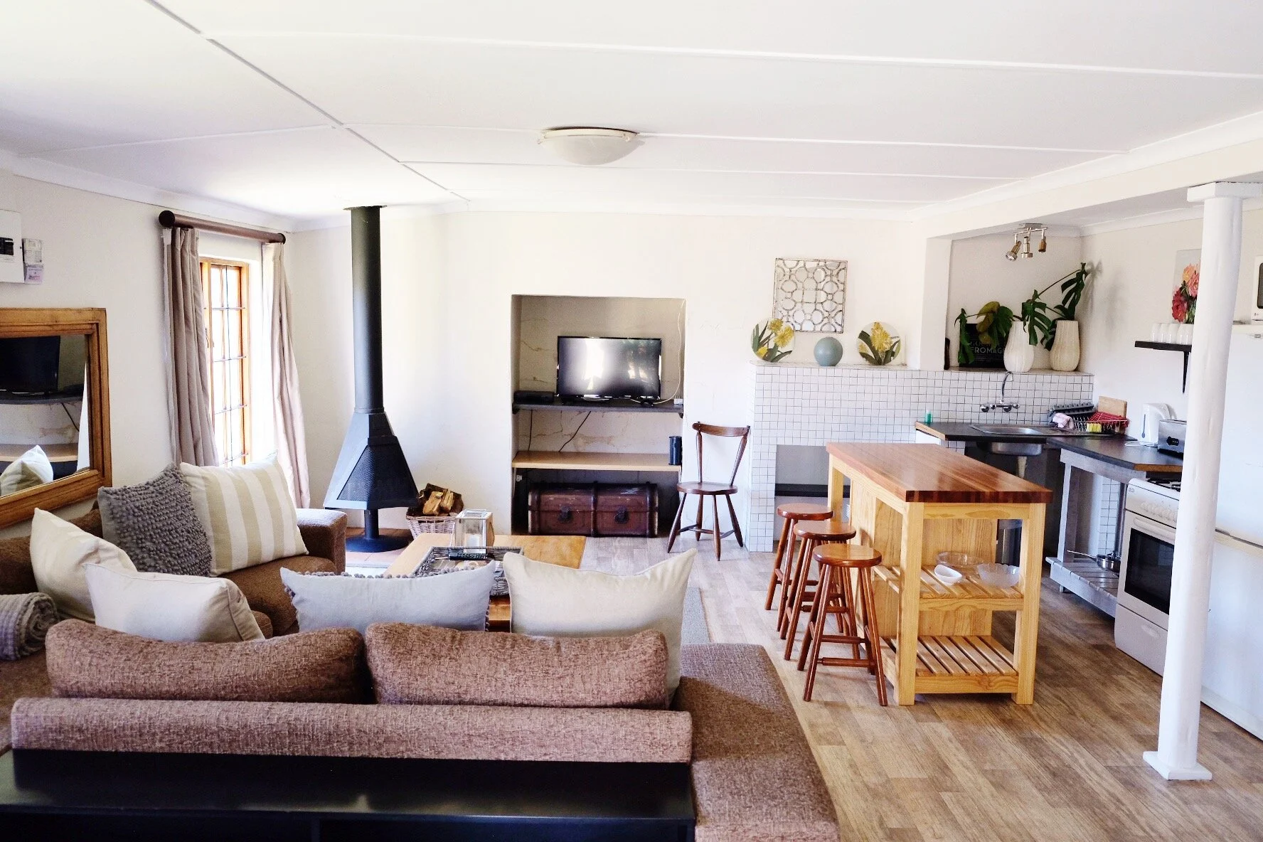 Open-plan lounge and kitchen with a fireplace in Reedbuck Cottage